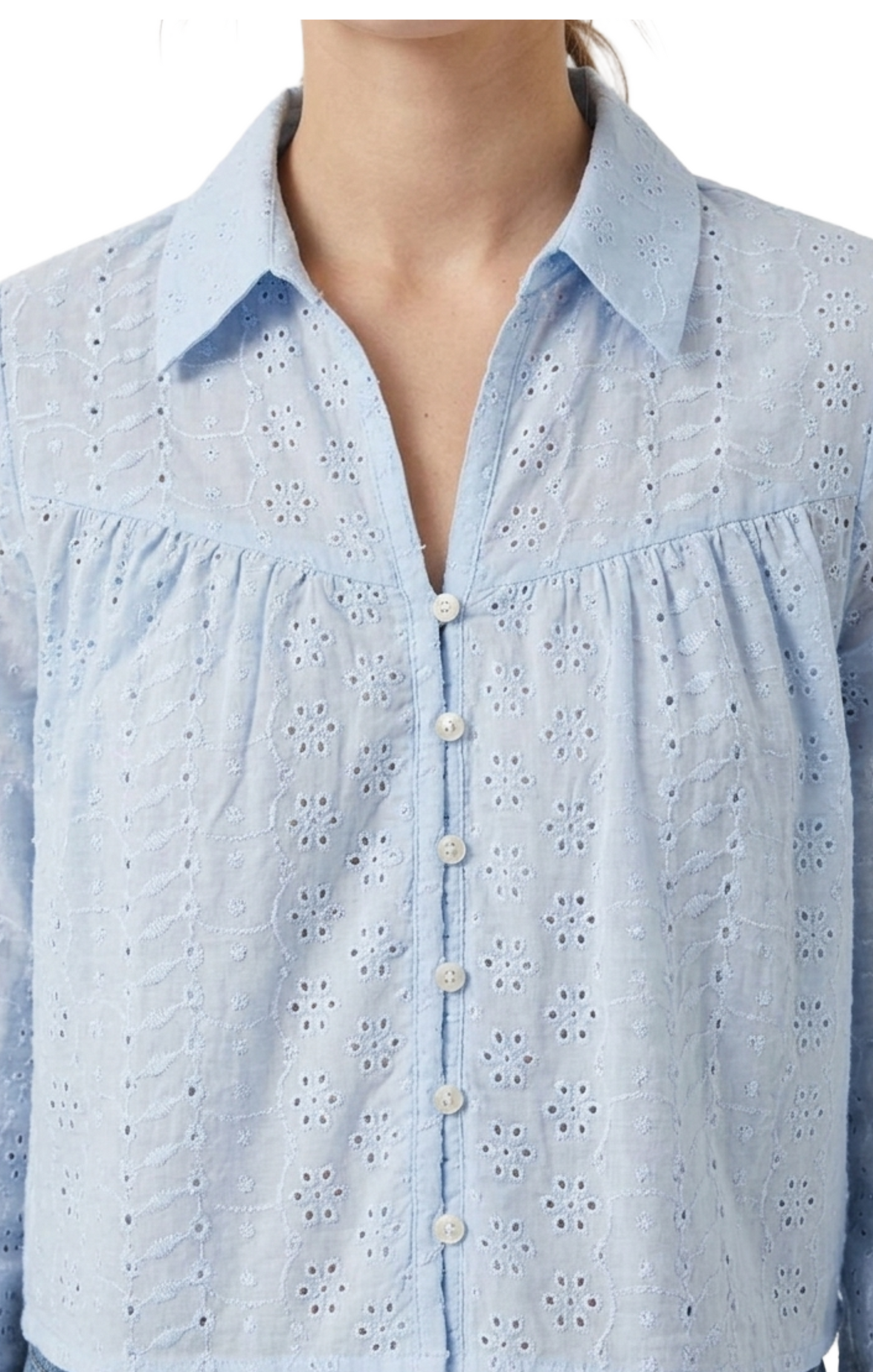 Blusa azul abotonada con perforaciones y bordados decorativos